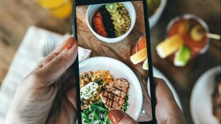 Jemand fotografiert sein Essen mit dem Smartphone