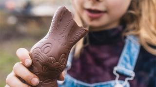 Mädchen hält angebissenen Schoko-Osterhasen