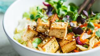 Schüssel mit Tofu-Salat. Im Hintergrund ragen Essstäbchen aus der Schüssel