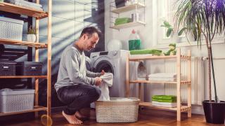 Mann kniet vor Waschmaschine